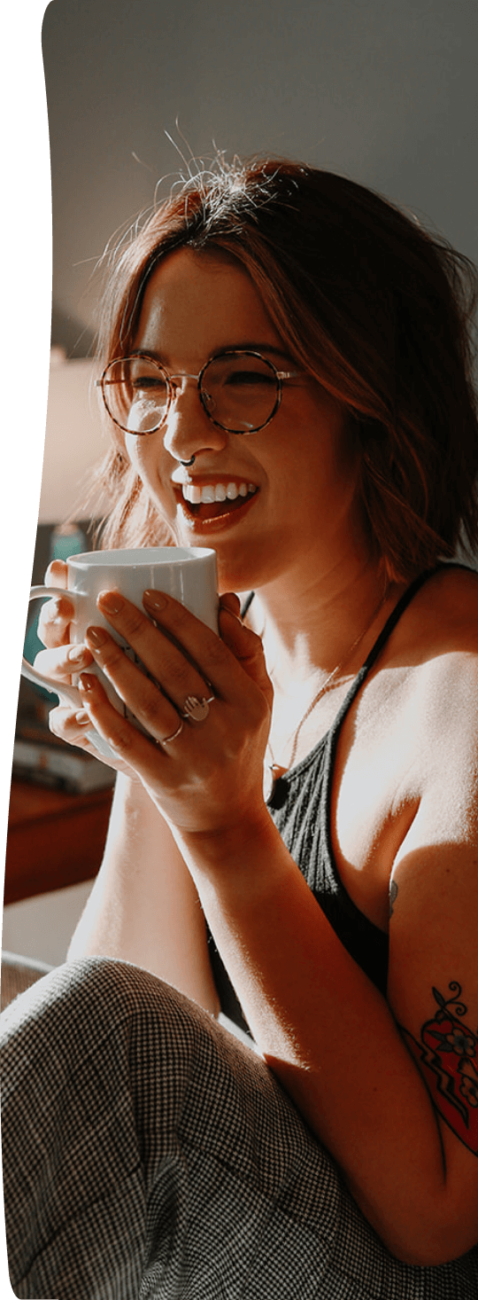 a young person wearing glasses and sipping a cup of coffee